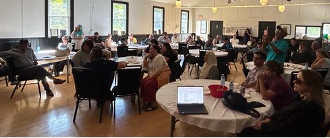 Residents seated at tables in a community hall during a local meeting.